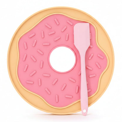 Pink donut-shaped mat with a spatula on a white surface